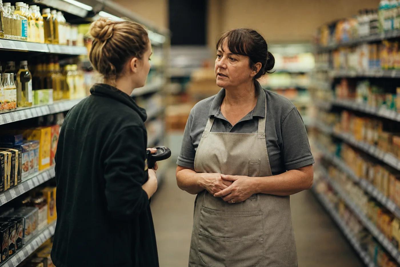 A shift supervisor talking with a colleague on the floor of a retail store